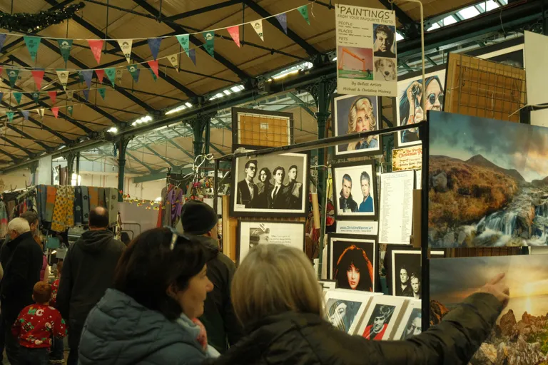 People browsing art at an outdoor market stall.