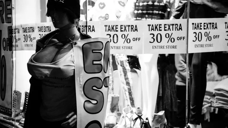 a woman holding a sale sign in front of a store