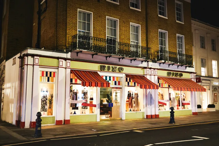A brightly lit storefront at night with mannequins displayed.